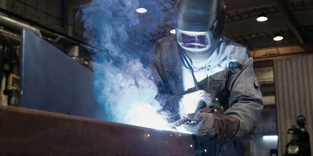 Schweißer bei der Arbeit mit VAUPEL Absaugtechnik in einem industriellen Umfeld, modernem Staub- und Rauchabsaugsystem.